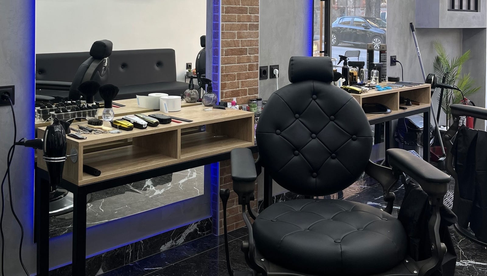 Το εσωτερικό του Plaza Barber Shop: μαύρο μάρμαρο, μπλε LED και οι δύο δερμάτινες πολυθρόνες